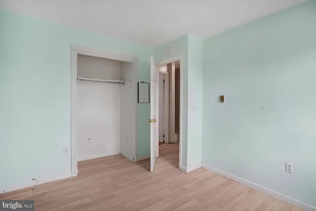an empty room with wooden floor and closet area
