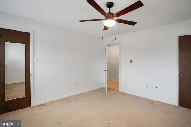 an empty room with a ceiling fan and a window