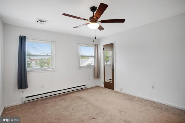 an empty room with ceiling fan and window