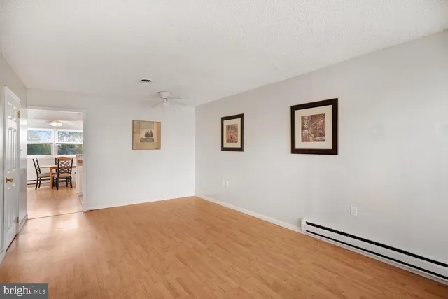 a view of empty room with wooden floor and fan