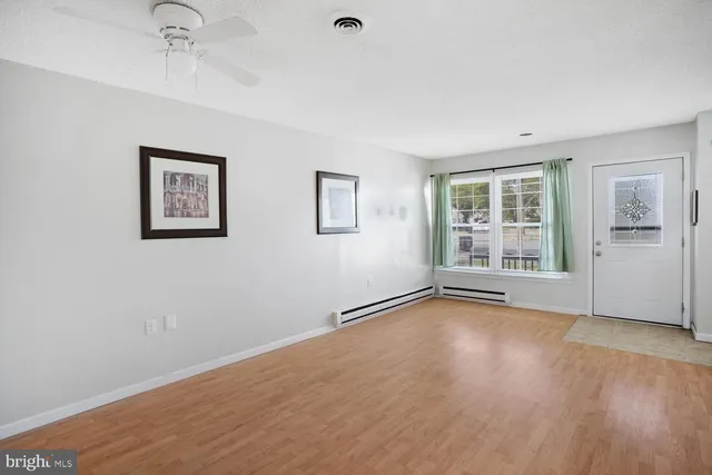 a view of an empty room with a window and wooden floor