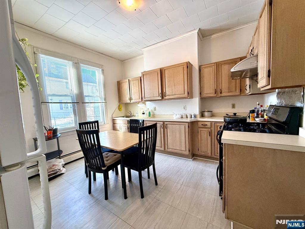 405 7th Street Harrison, NJ 07029 - Photo 6 of 21 a kitchen with stainless steel appliances granite countertop a stove a sink dishwasher a microwave oven a dining table and chairs with wooden floor