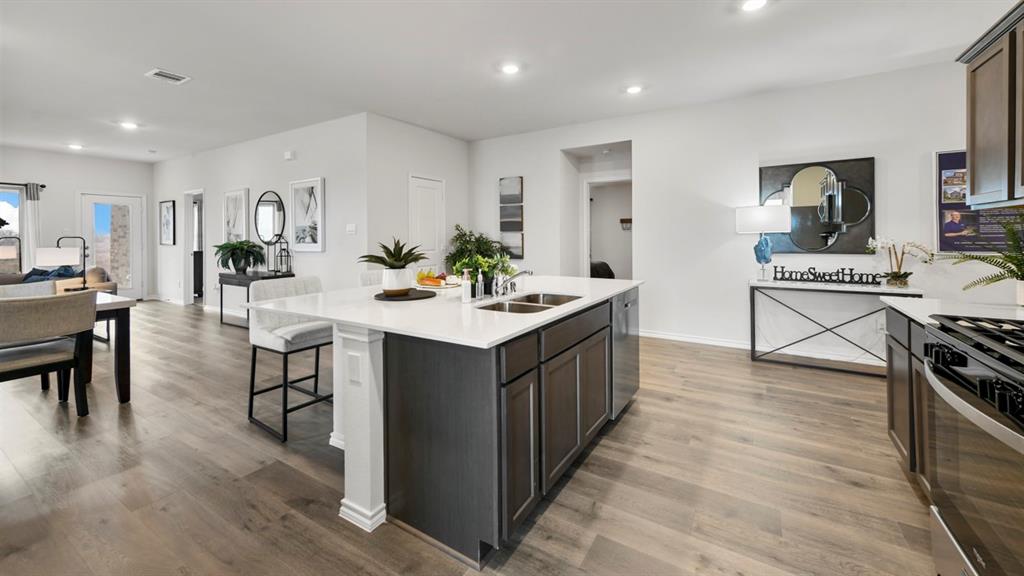 1671 Mantle Road Crandall, TX 75114 - Photo 4 of 24 Spacious kitchen featuring a central island with a solid surface countertop, dark wood-finish cabinetry, stainless steel appliances, and wood-finish flooring