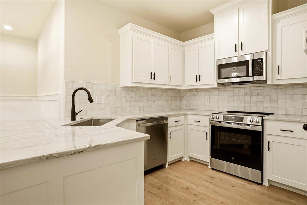206 Legacy Boulevard Weatherford, TX 76086 - Photo 8 of 21 a kitchen with stainless steel appliances granite countertop a sink stove and microwave
