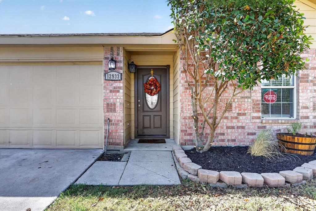 Brick facade with a neutral-toned garage door, front entry door with an oval glass insert, and an exterior sconce