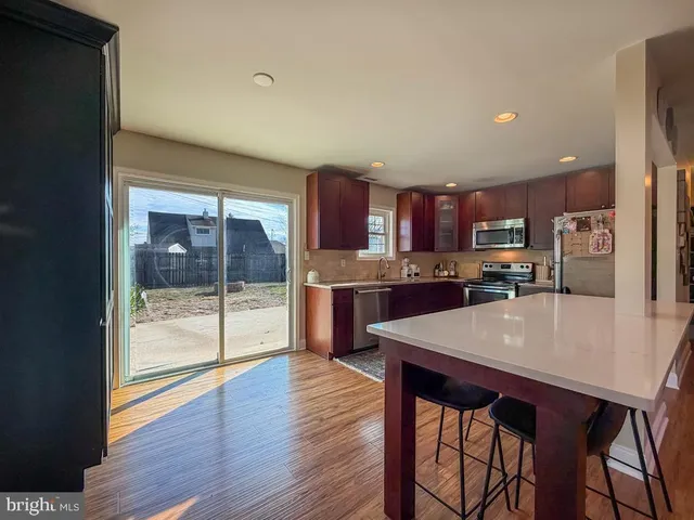 a large kitchen with stainless steel appliances granite countertop wooden floors a refrigerator and wooden cabinets