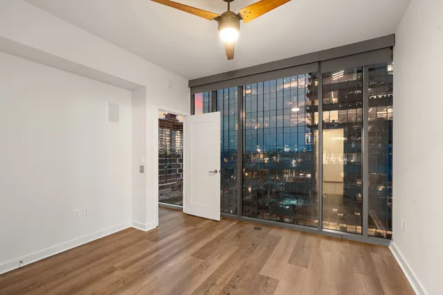 a view of an empty room with window and wooden floor