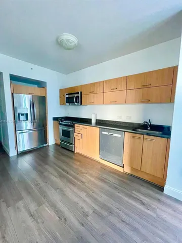 a view of kitchen with stainless steel appliances wooden floor and window