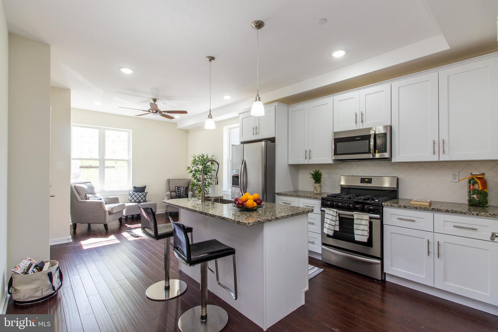 a open kitchen with stainless steel appliances granite countertop a stove and white cabinets with wooden floor