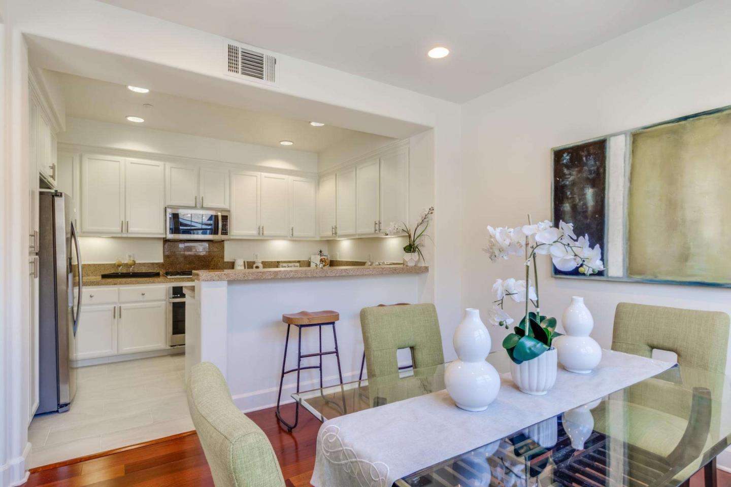 100 Live Oak Way, Unit 104 Belmont, CA 94002 - Photo 11 of 37 a kitchen with stainless steel appliances granite countertop a table chairs sink and cabinets