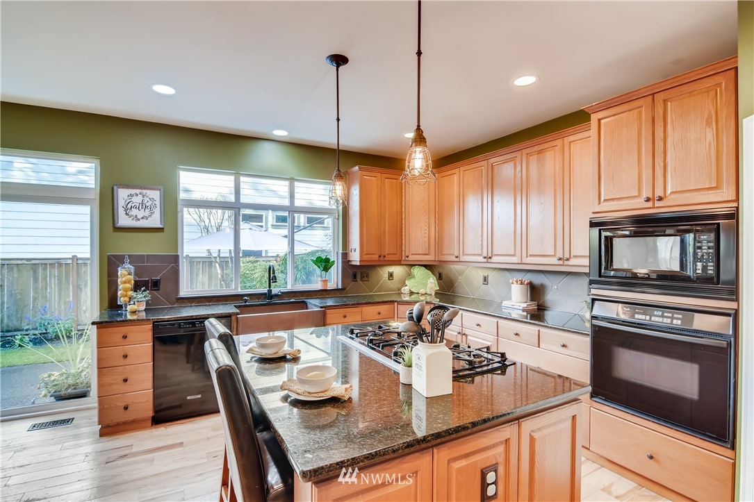 16530 Parkside Way Southeast Renton, WA 98058 - Photo 7 of 25 a kitchen with stainless steel appliances granite countertop wooden floor sink stove and wooden cabinets