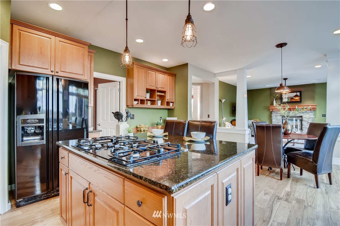 16530 Parkside Way Southeast Renton, WA 98058 - Photo 8 of 25 a kitchen with stainless steel appliances kitchen island granite countertop a stove a refrigerator a kitchen island a couches and chairs with wooden floor