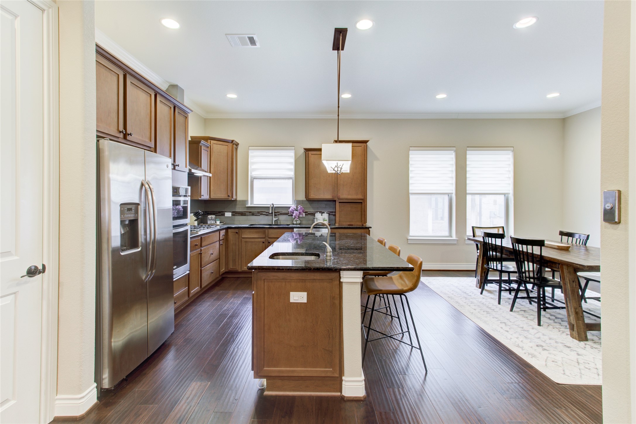 224 Adams Street Georgetown, TX 78628 - Photo 16 of 34 a kitchen with stainless steel appliances granite countertop a refrigerator a stove top oven a dining table and chairs with wooden floor