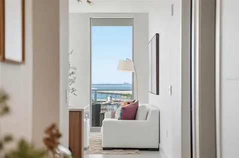 a living room with furniture large windows and wooden floor