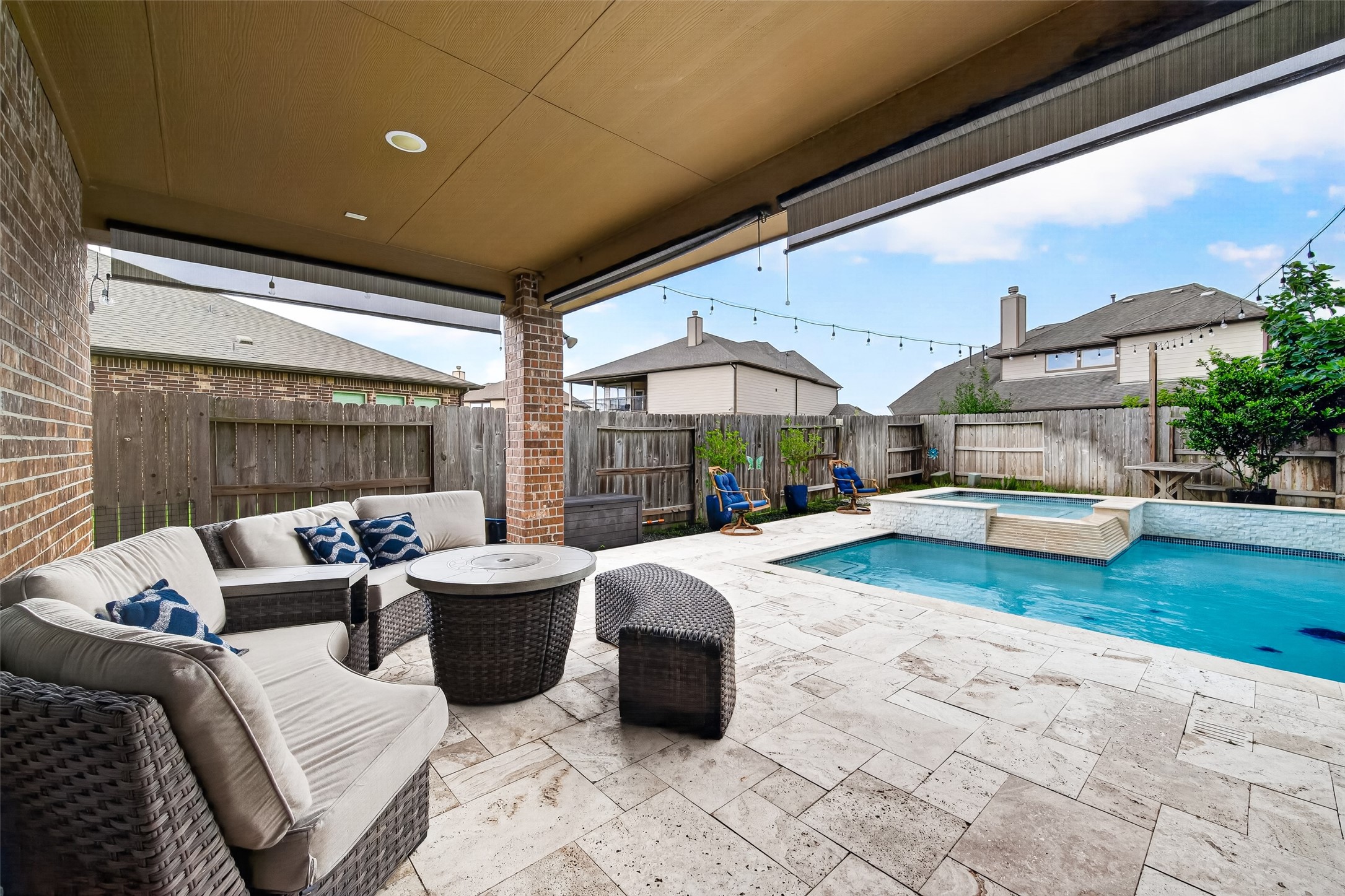 25611 Ellis Ridge Court Katy, TX 77494 - Photo 45 of 49 This backyard oasis features a covered patio with comfortable seating and a fire pit, overlooking a sparkling pool with a waterfall feature. Perfect for relaxation and entertaining.
