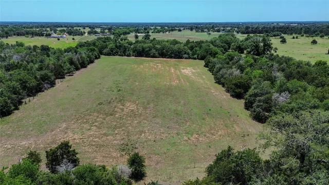 an aerial view of a houses with outdoor space and trees all around