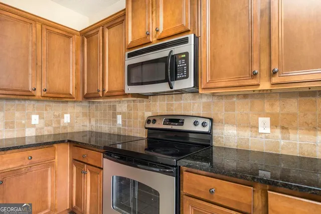 a kitchen with stainless steel appliances granite countertop white cabinets and a stove top oven