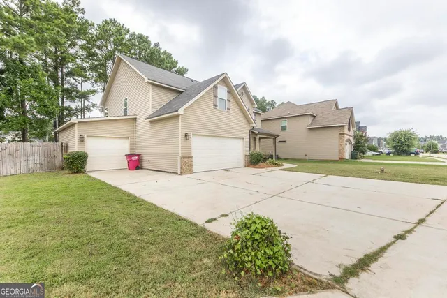 a view of a white house with a yard and large tree