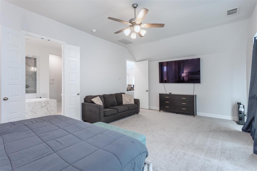 9110 Copperhead Road Little Elm, TX 75068 - Photo 18 of 35 a spacious bedroom with a bed and a flat screen tv
