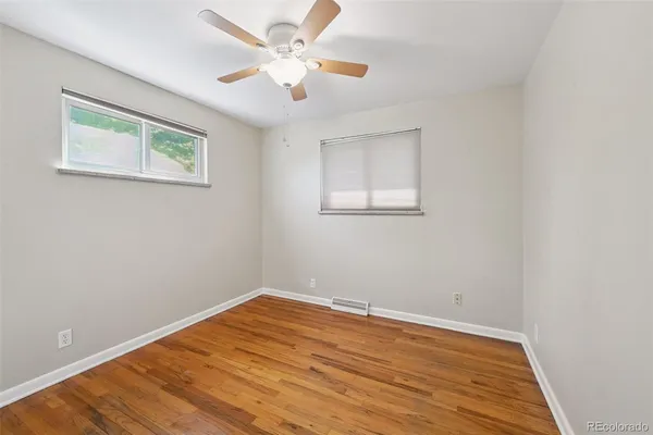 a view of a room with wooden floor and a ceiling fan