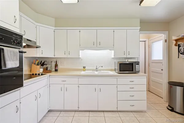 a kitchen with white cabinets and appliances