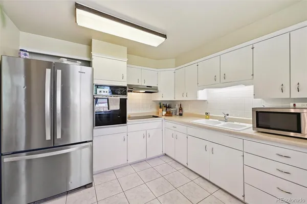 a kitchen with white cabinets white stainless steel appliances and sink