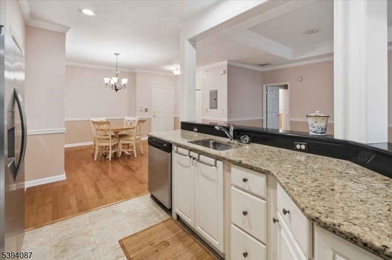 a kitchen with granite countertop a sink a stove a dining table and chairs