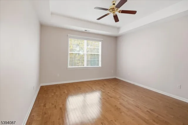 an empty room with wooden floor closet and windows