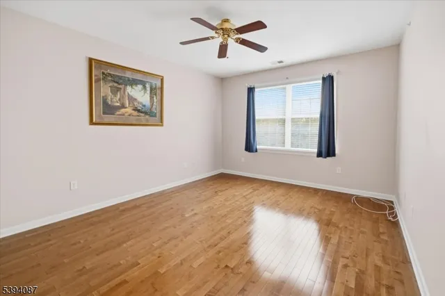 a view of an empty room with window and a chandelier fan