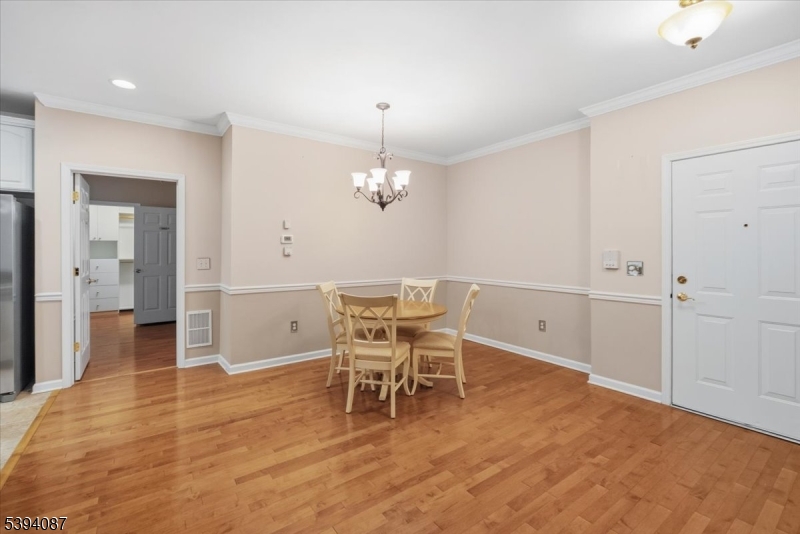 89 Ridgeview Lane, Unit 89 Mount Arlington, NJ 07856 - Photo 4 of 43 a dining room with wooden floor a chandelier a wooden table and chairs