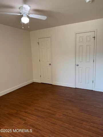 a view of an empty room with wooden floor a ceiling fan and closet area
