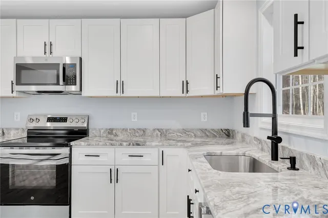 a kitchen with stainless steel appliances granite countertop a sink a stove and a microwave