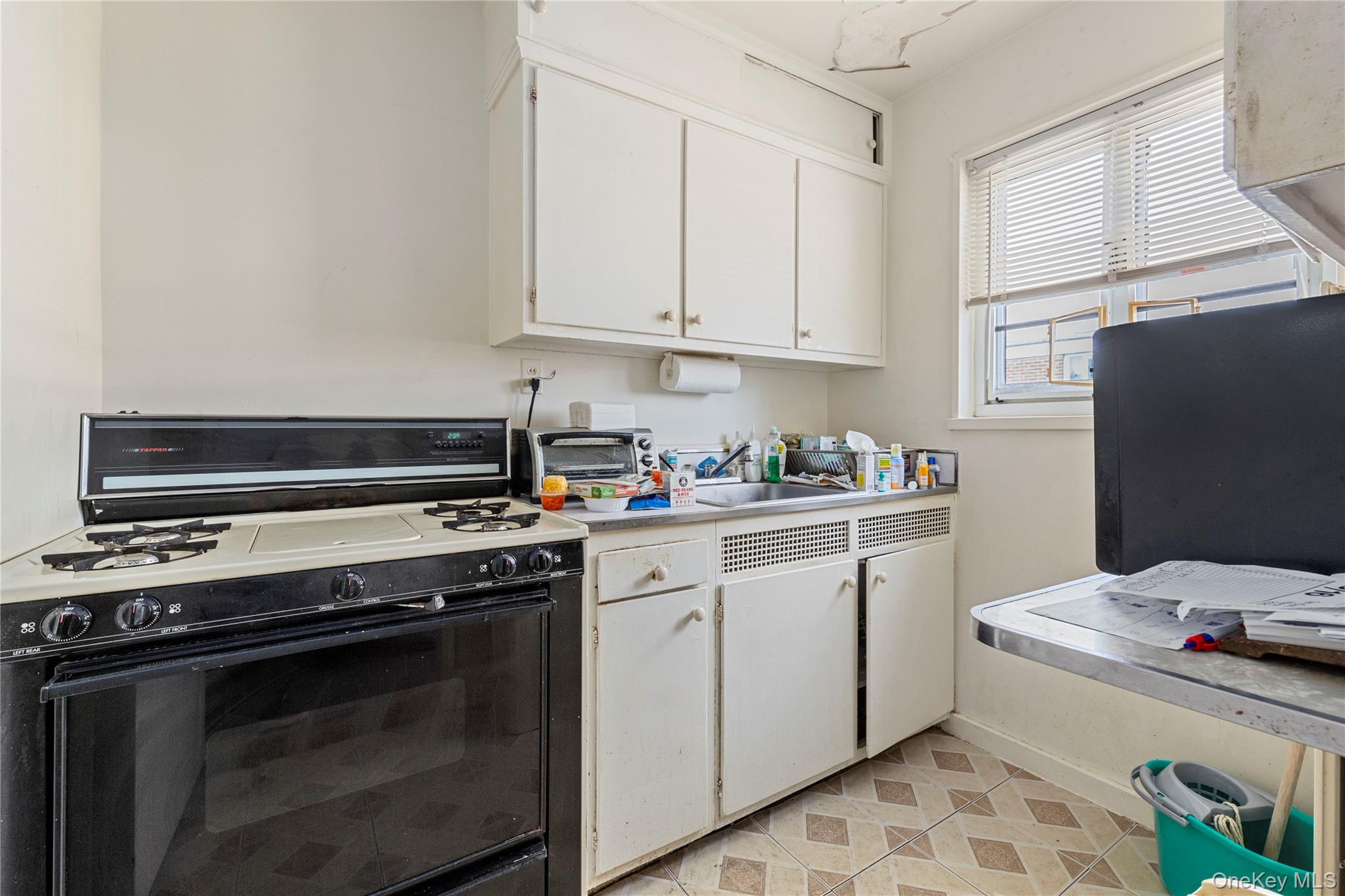 221-31 Braddock Avenue, Unit UPPR Queens, NY 11427 - Photo 13 of 16 a kitchen with a stove and white cabinets
