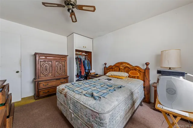 a bedroom with a bed and dresser with wooden floor