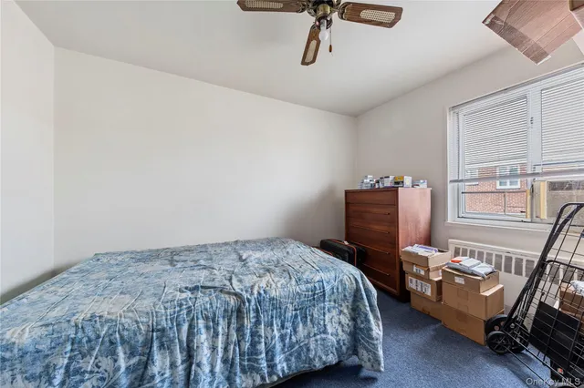 a bedroom with a bed a dresser and the window