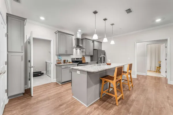 a kitchen with stainless steel appliances a dining table chairs stove refrigerator and cabinets