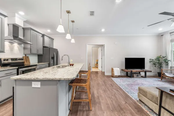a kitchen with stainless steel appliances granite countertop a sink a stove and a wooden floors