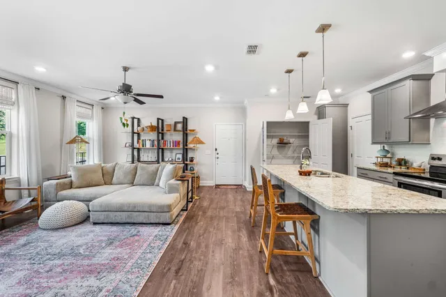 a living room with furniture kitchen view and a wooden floor