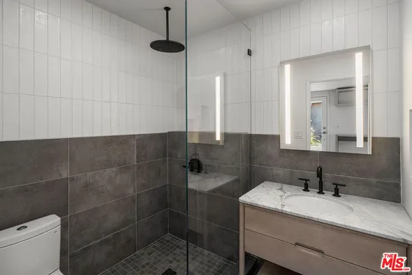 a bathroom with a granite countertop sink a toilet and a mirror