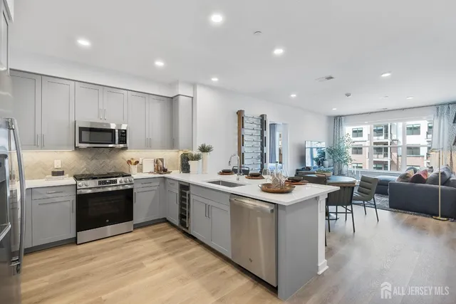 a kitchen with stainless steel appliances granite countertop a stove top oven a sink dishwasher a dining table and chairs with wooden floor