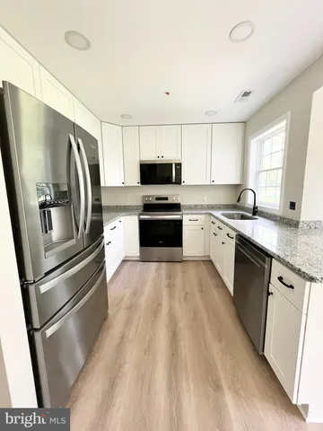 a kitchen with granite countertop a refrigerator oven a sink and dishwasher