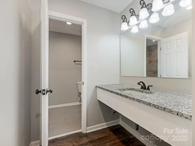 a bathroom with a granite countertop sink a light fixture and a mirror