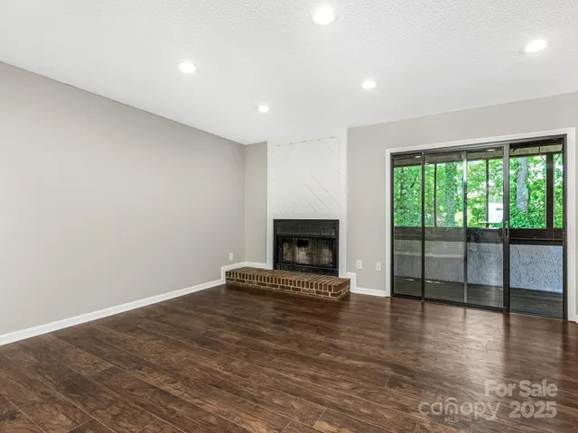 a view of empty room with wooden floor and fireplace