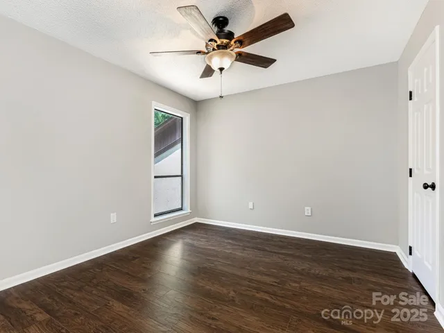 a view of an empty room with window and wooden floor