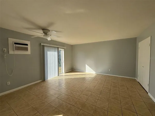 a view of an empty room with window and chandelier fan