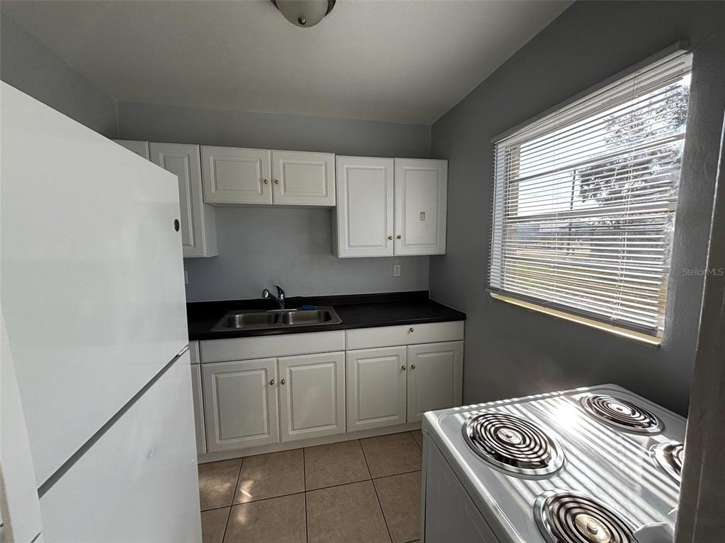 310 Farnol Street Southwest, Unit 3 Winter Haven, FL 33880 - Photo 6 of 9 a kitchen with granite countertop a sink stove and cabinets