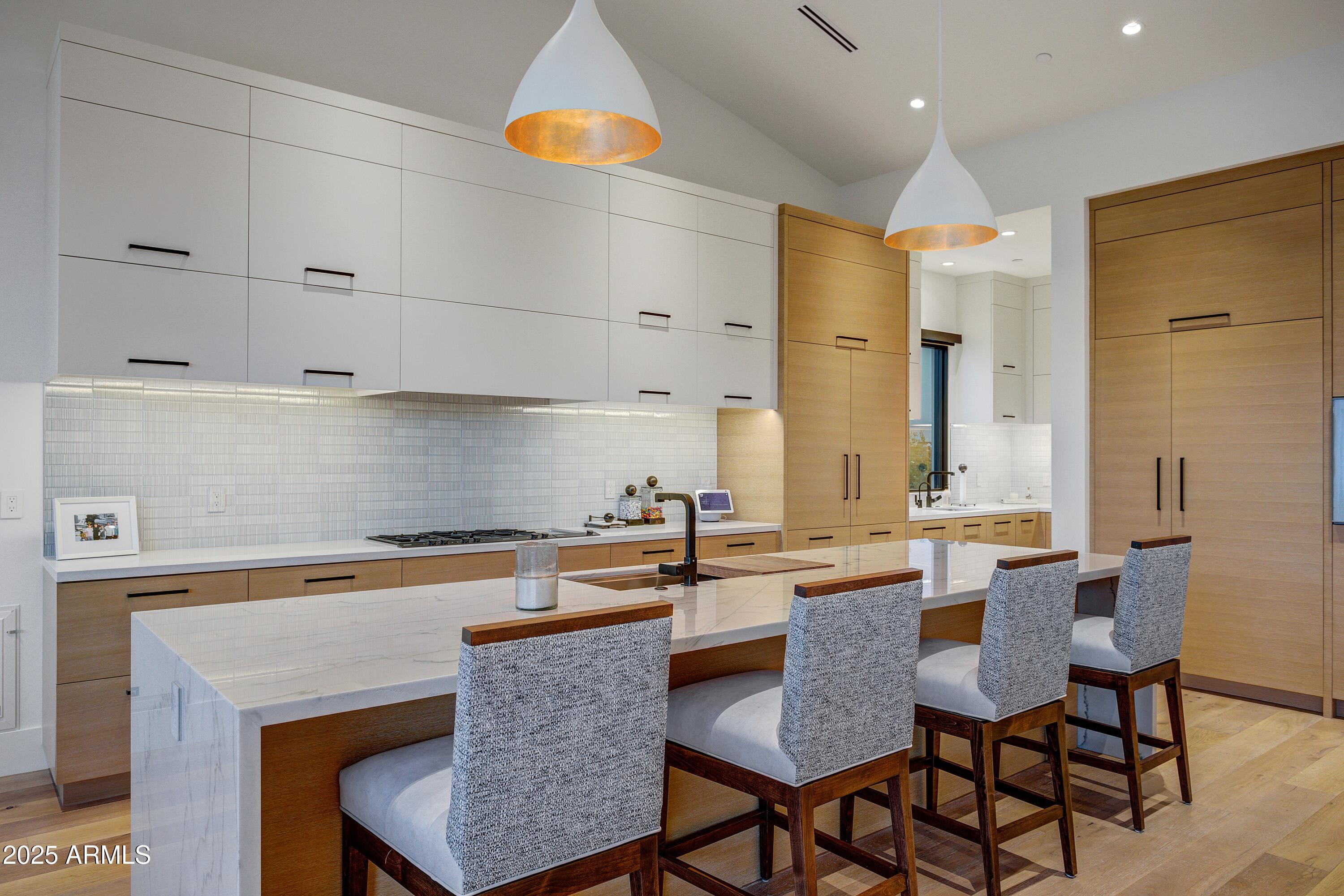 6930 East Cactus Wren Road Paradise Valley, AZ 85253 - Photo 10 of 26 a kitchen with stainless steel appliances granite countertop a table chairs in it and white cabinets