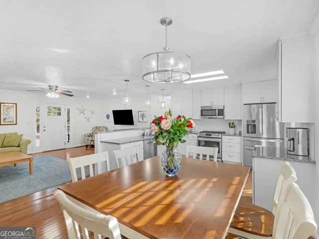 a dining room with kitchen island stainless steel appliances furniture a chandelier and kitchen view