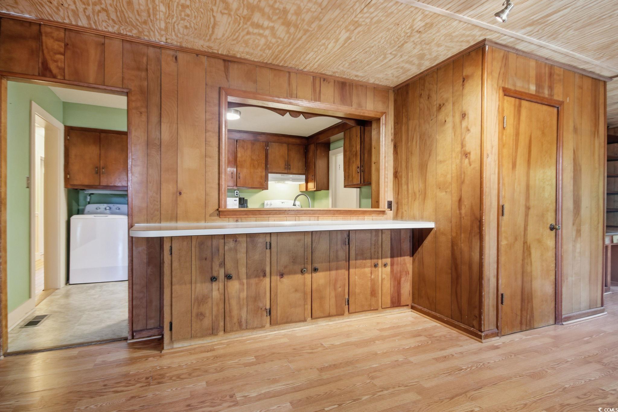 2206 Beck Street Georgetown, SC 29440 - Photo 15 of 36 Kitchen with wooden walls, washer / dryer, light wood-type flooring, light countertops, and brown cabinetry