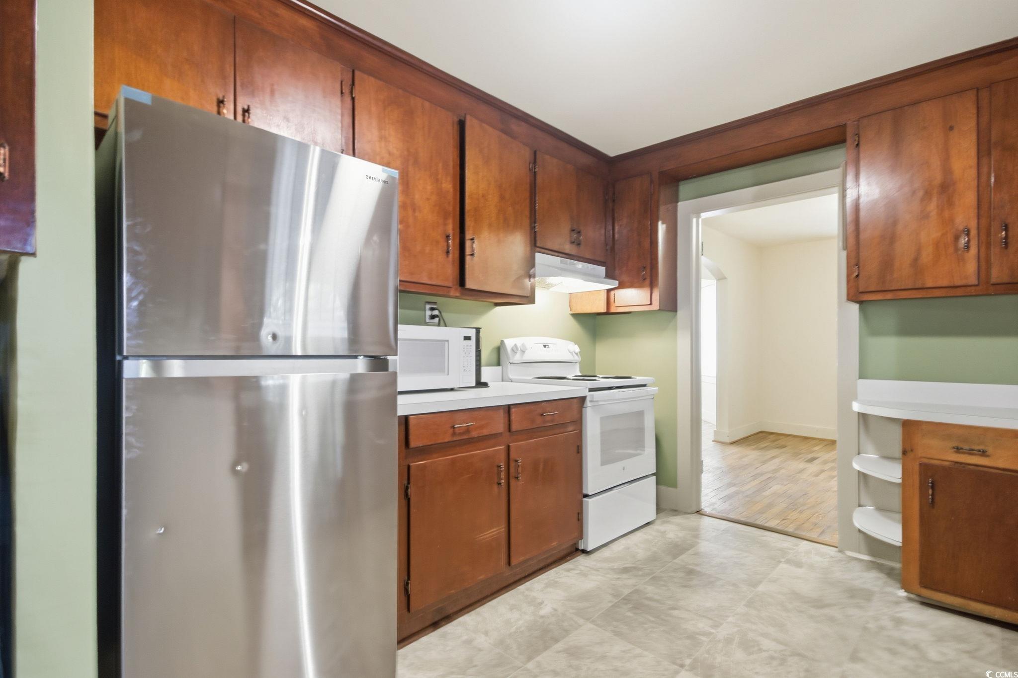 2206 Beck Street Georgetown, SC 29440 - Photo 10 of 36 Kitchen with white appliances, light countertops, under cabinet range hood, and brown cabinetry